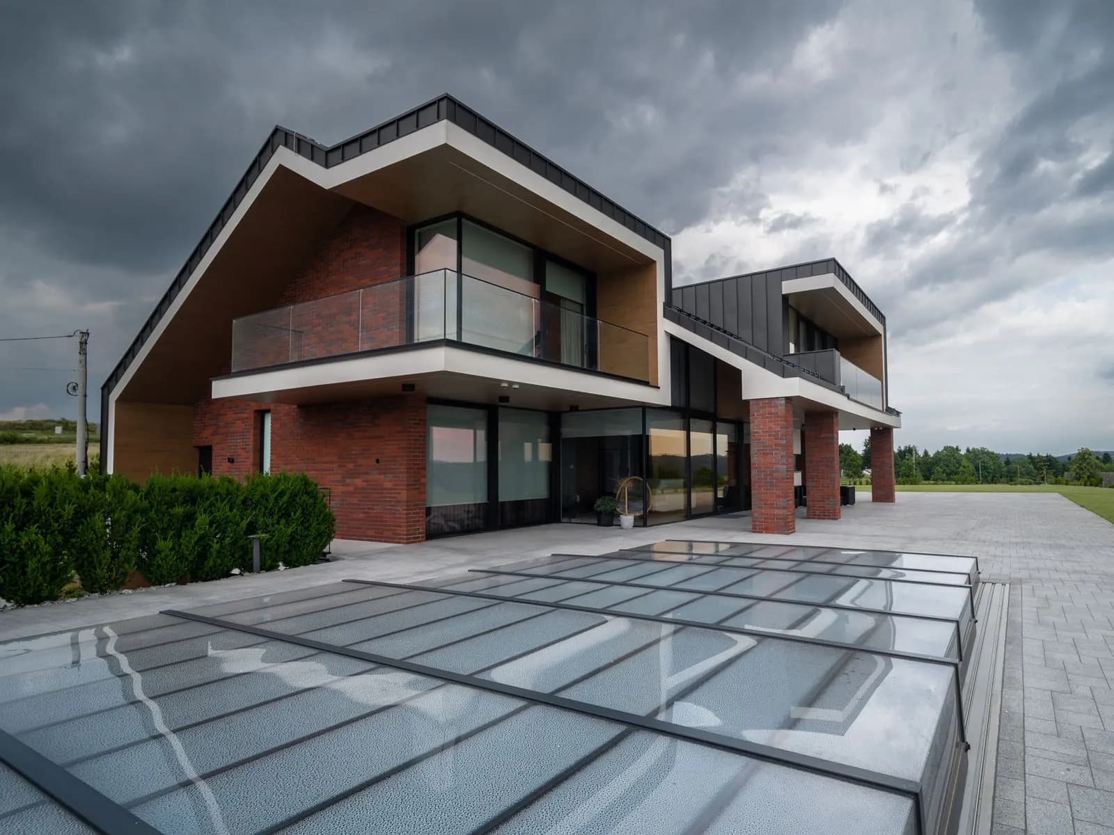Villa met schuine daklijn, baksteen en glazen gevel bij het zwembad