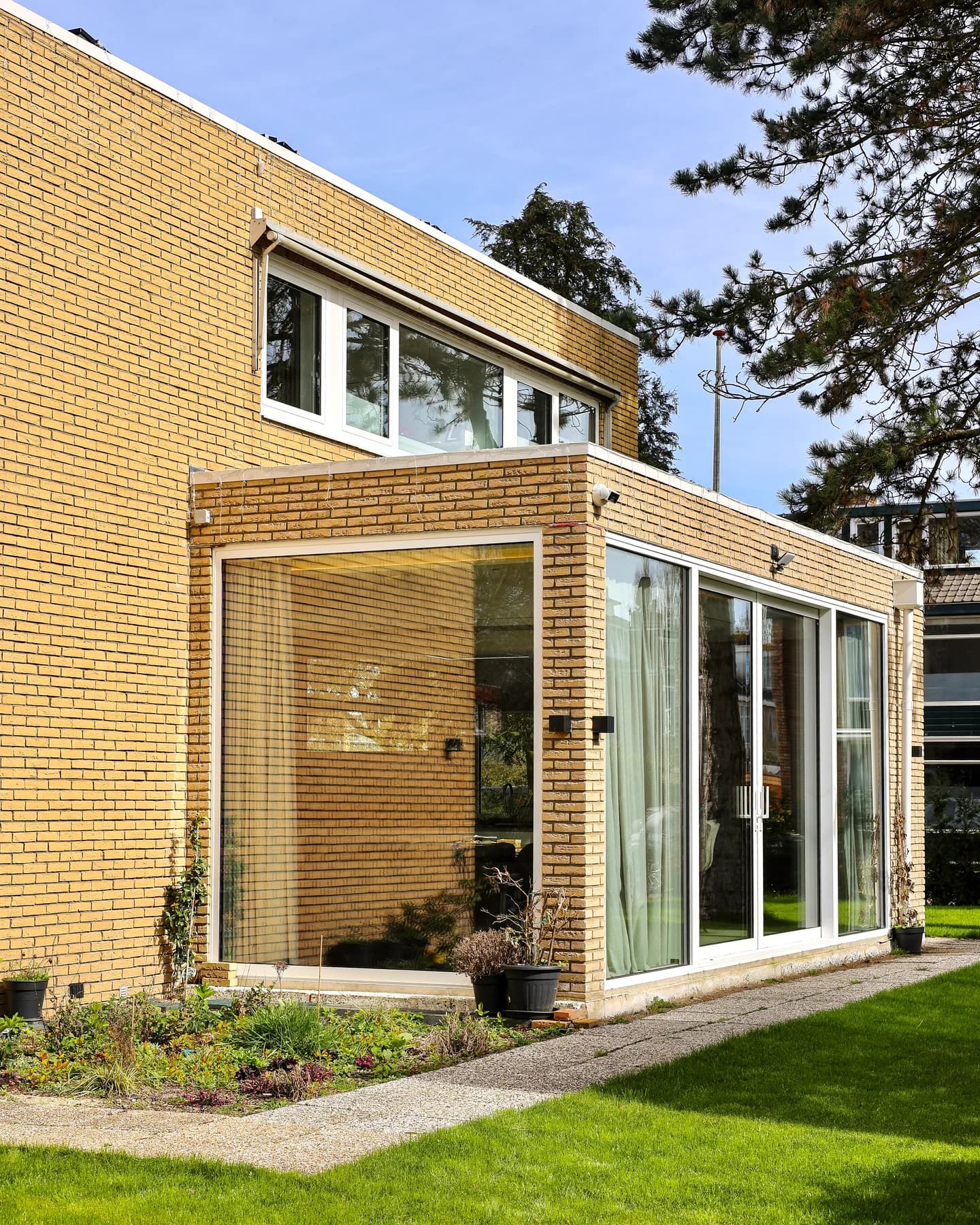 Zijaanzicht van de bakstenen woning met glazen aanbouw