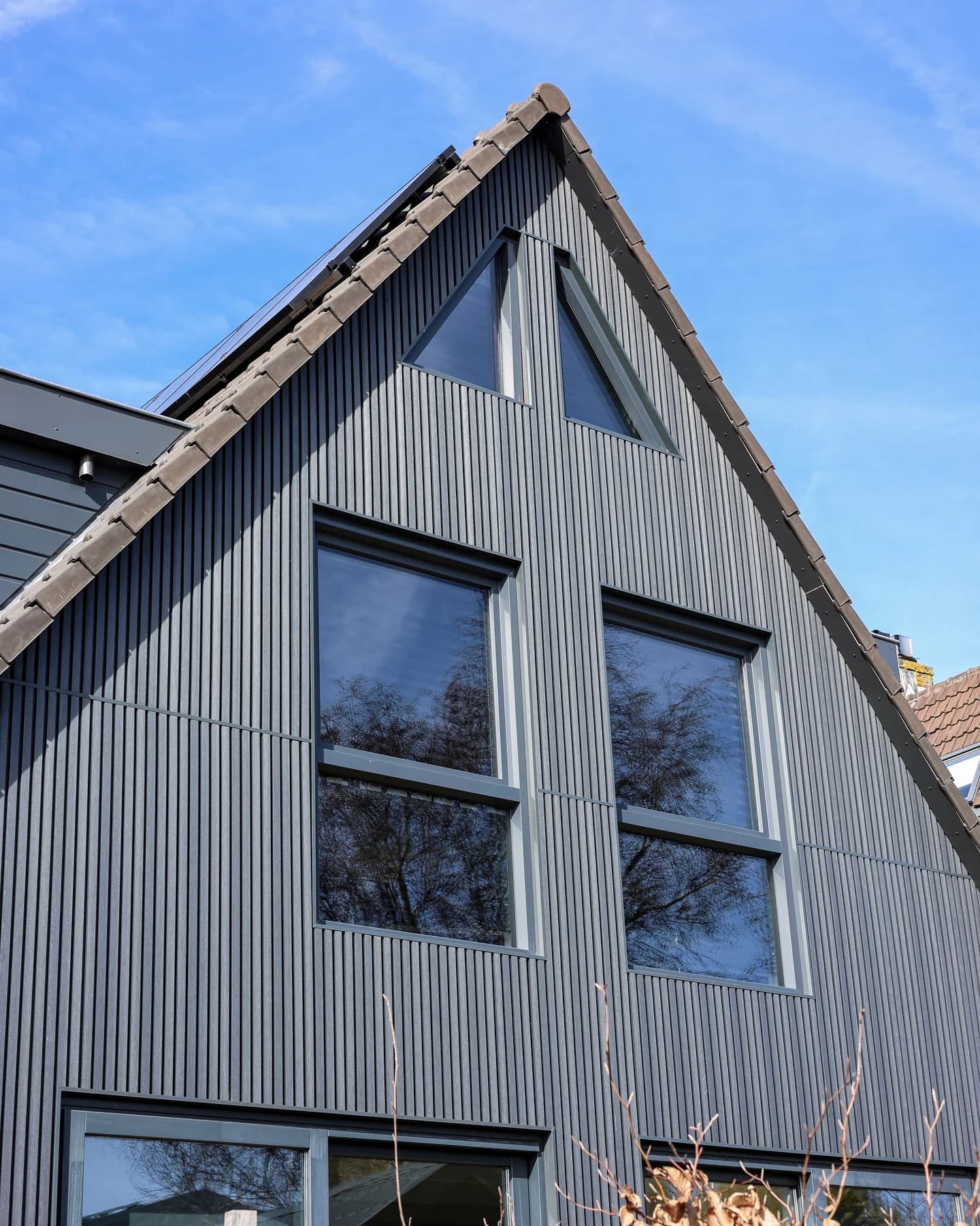 Corner view of the dark home with bespoke windows