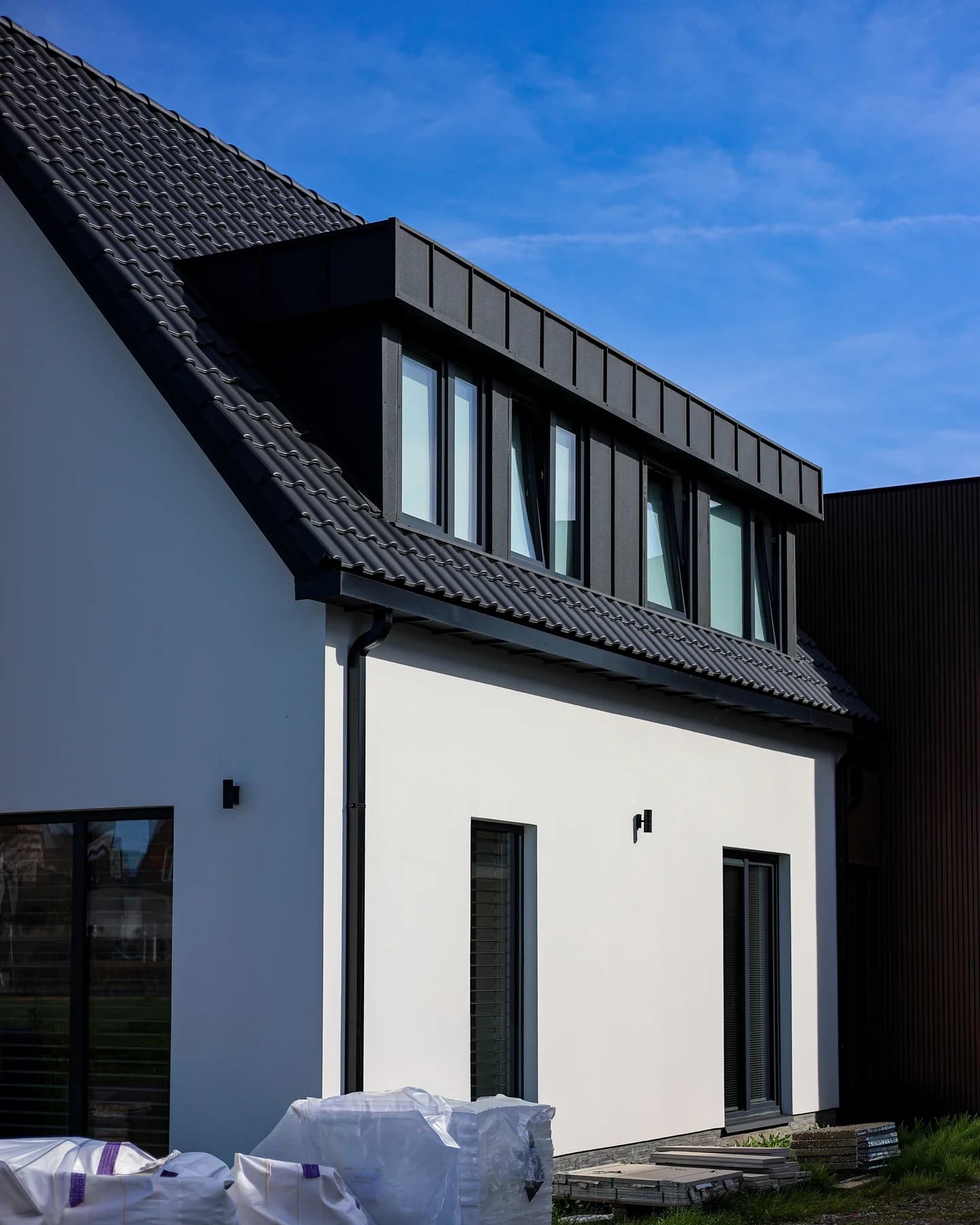 Witte woning met zwarte dakafwerking en slanke ramen