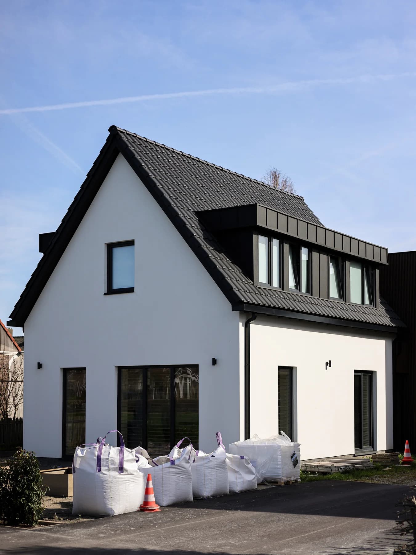 Overzicht van de witte woning met donkere raamkozijnen