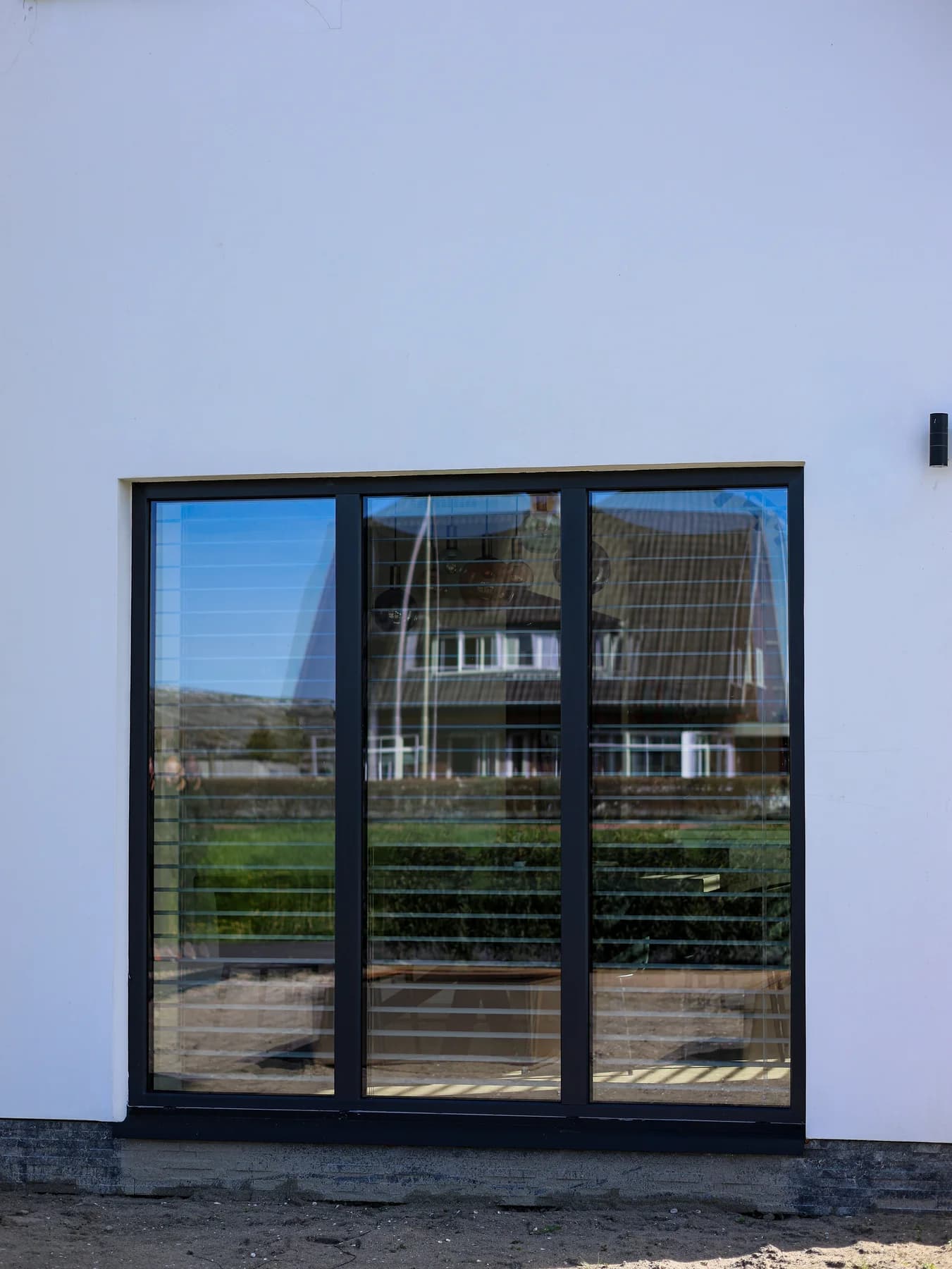 Glazen tuindeur in een strak wit gestucte gevel