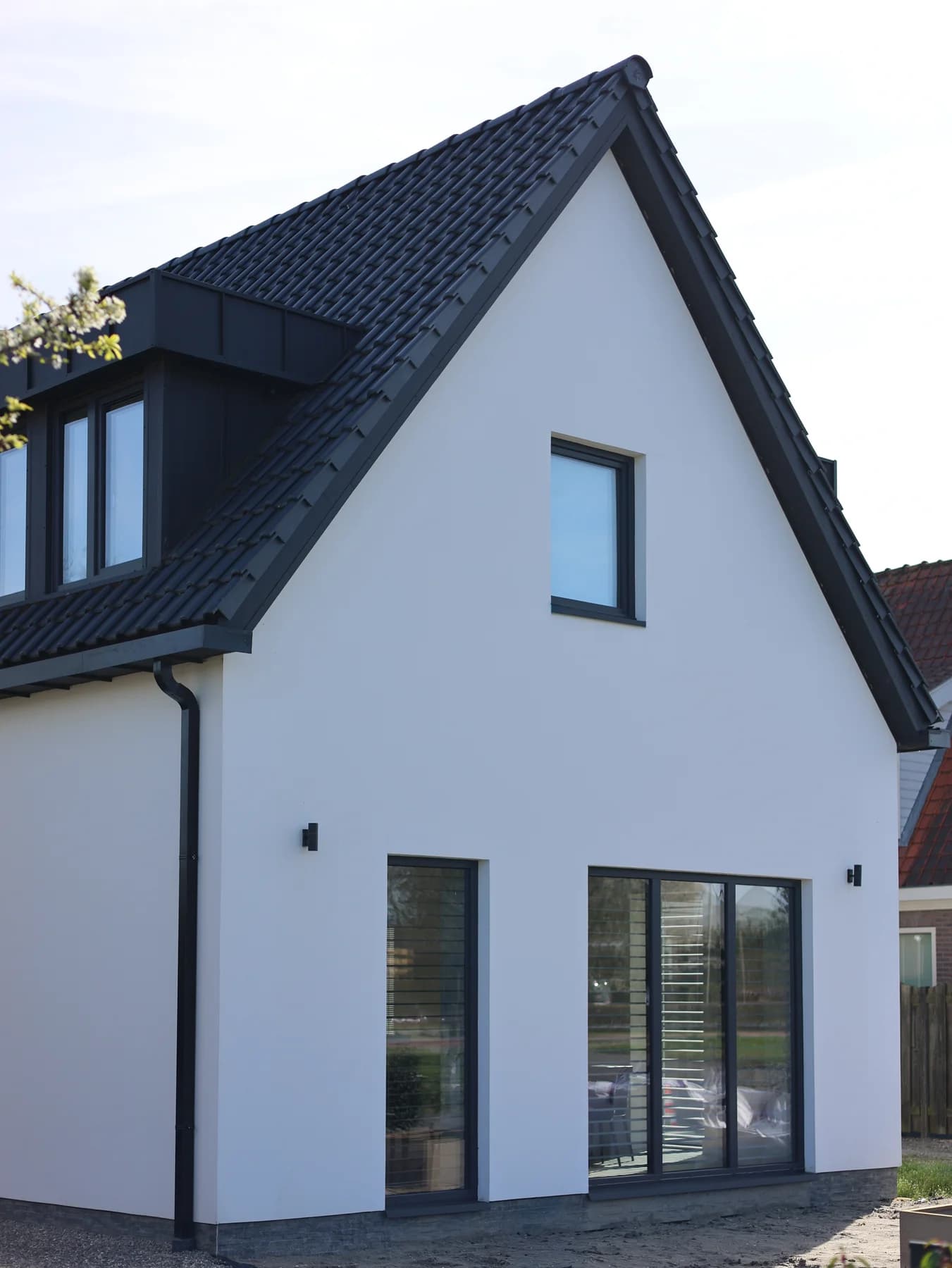 Witte zijgevel met raam en tuindeur